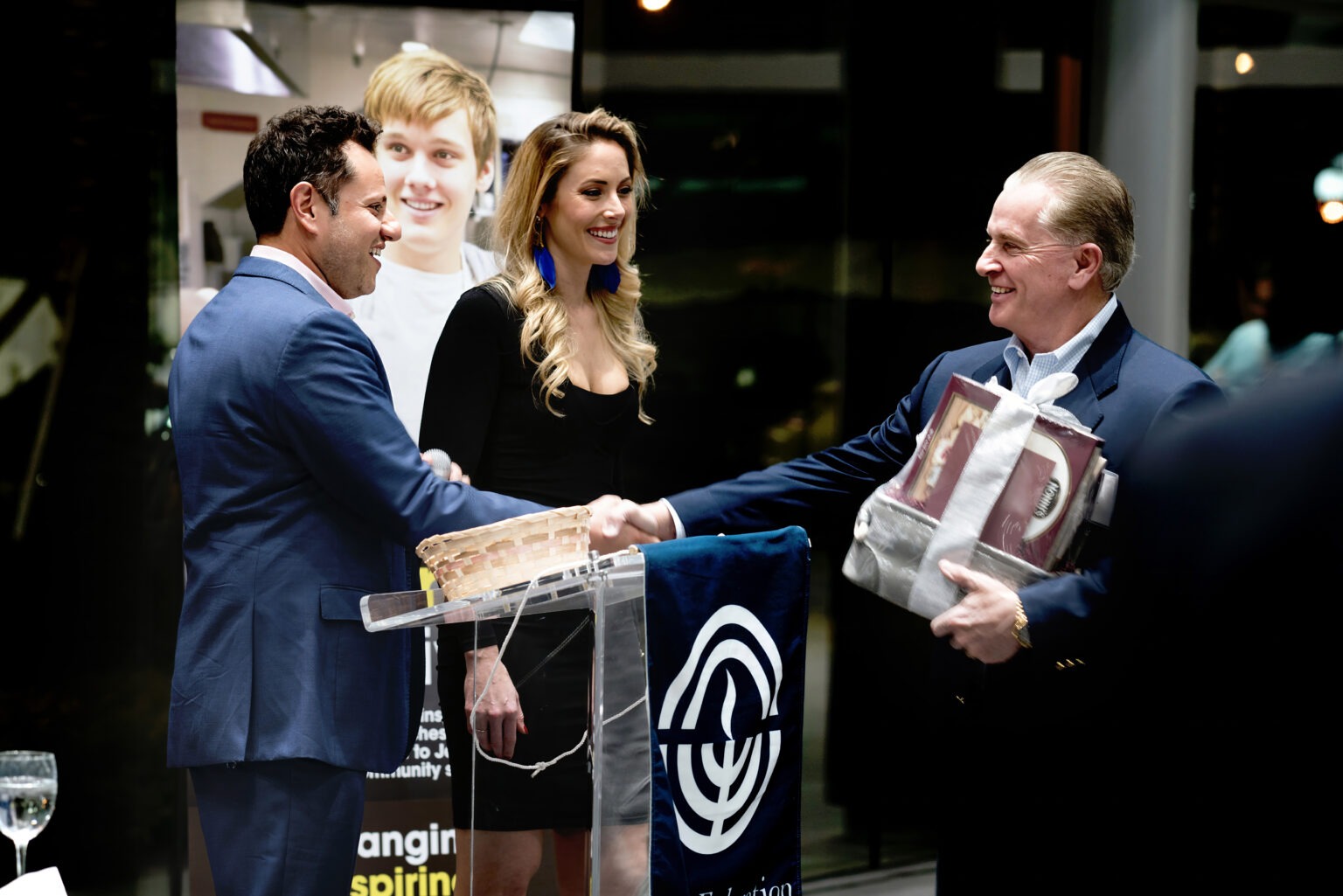 Guests exchange gifts and handshakes during an elegant Jewish Federation of Palm Beach County event at Porsche Palm Beach, photographed by David Scarola Photography.Jewish Federation of Palm Beach County, Porsche Palm Beach event photography, luxury corporate event photographer, Palm Beach gala photographer, global event photographer, philanthropic event photography, high-end event photographer Florida, worldwide corporate photography, luxury brand photography, David Scarola Photography, Palm Beach luxury events, professional event photographer Palm Beach.