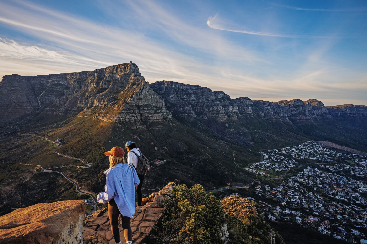 Two adventurers hiking along the edge of Lion’s Head Mountain in Cape Town, South Africa, during the International Academy of Trial Lawyers Annual Global Adventure. Captured in golden-hour light with Table Mountain in the background — a masterful blend of landscape, human spirit, and storytelling by David Scarola Photography.Lion’s Head Cape Town photography, Table Mountain photographer, South Africa adventure photography, global event photographer, International Academy of Trial Lawyers, international corporate retreat photography, world travel photography, Cape Town landscape photographer, adventure travel photographer, David Scarola Photography, luxury travel photography, corporate adventure coverage, destination event photographer, high-end global photographer, international law conference photography, Cape Town summit photography, outdoor team adventure, full coverage global events, fine art travel imagery, Cape Town sunrise hike photography.