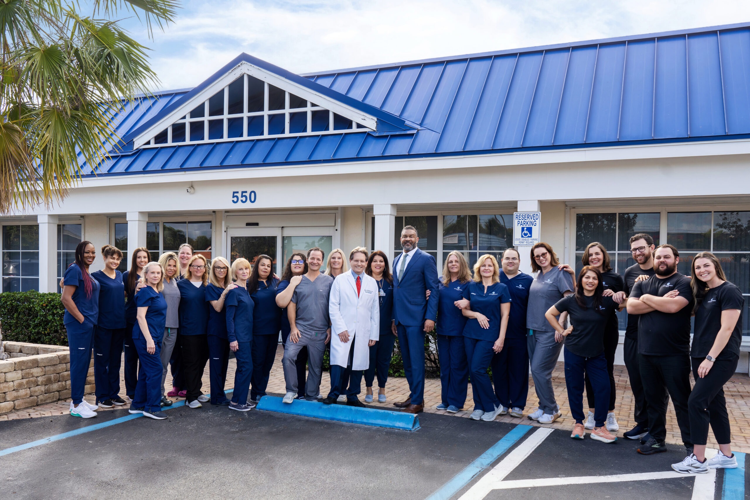 Dr. Craig Lichtblau and his full medical and rehabilitation team standing in front of their Palm Beach Gardens clinic at 550 Riverside Drive, captured by David Scarola Photography.