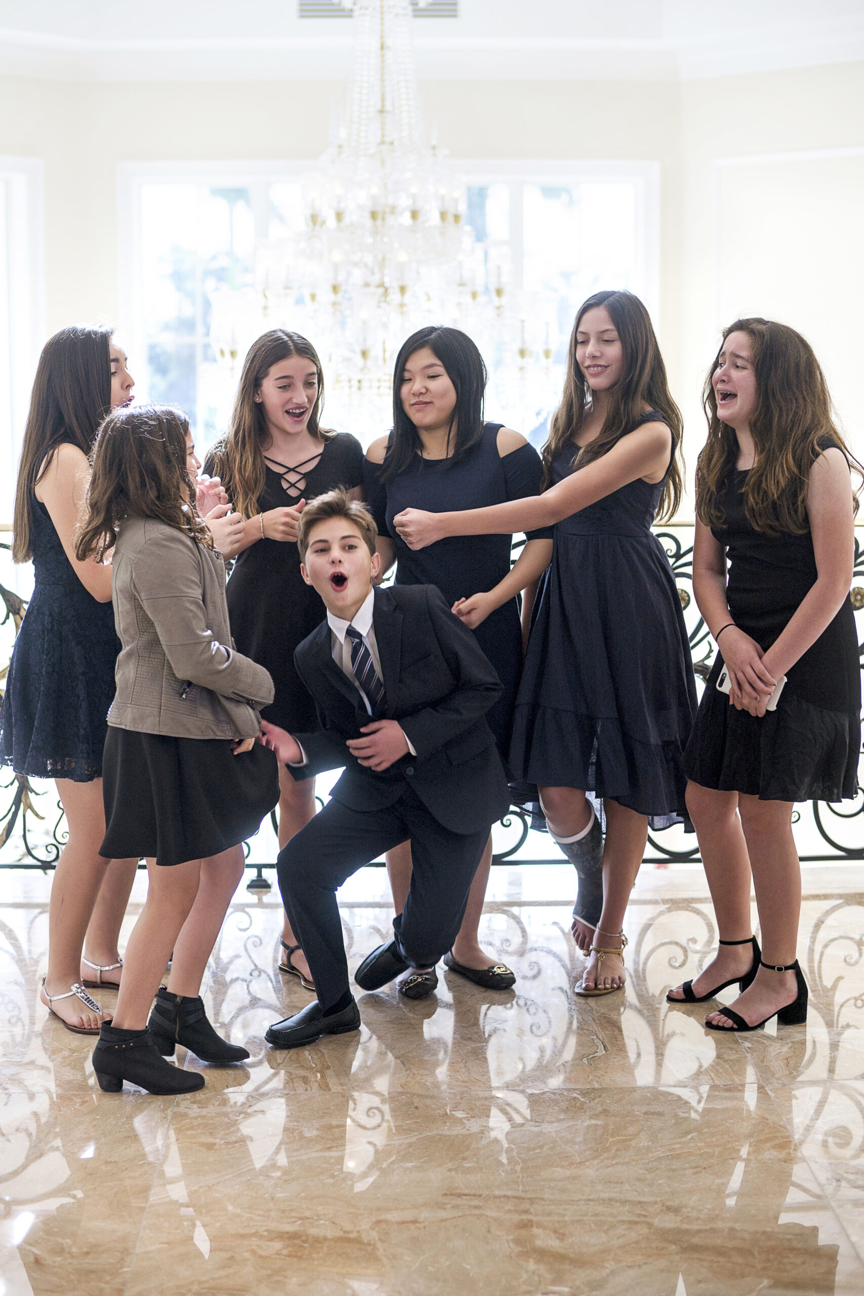 Matthew Smith celebrates his Bar Mitzvah at Trump National in Jupiter Island, Florida, surrounded by friends in laughter and joy. The young guests share a lively moment in the grand ballroom beneath an elegant chandelier, perfectly capturing the spirit of youthful celebration and refined luxury.