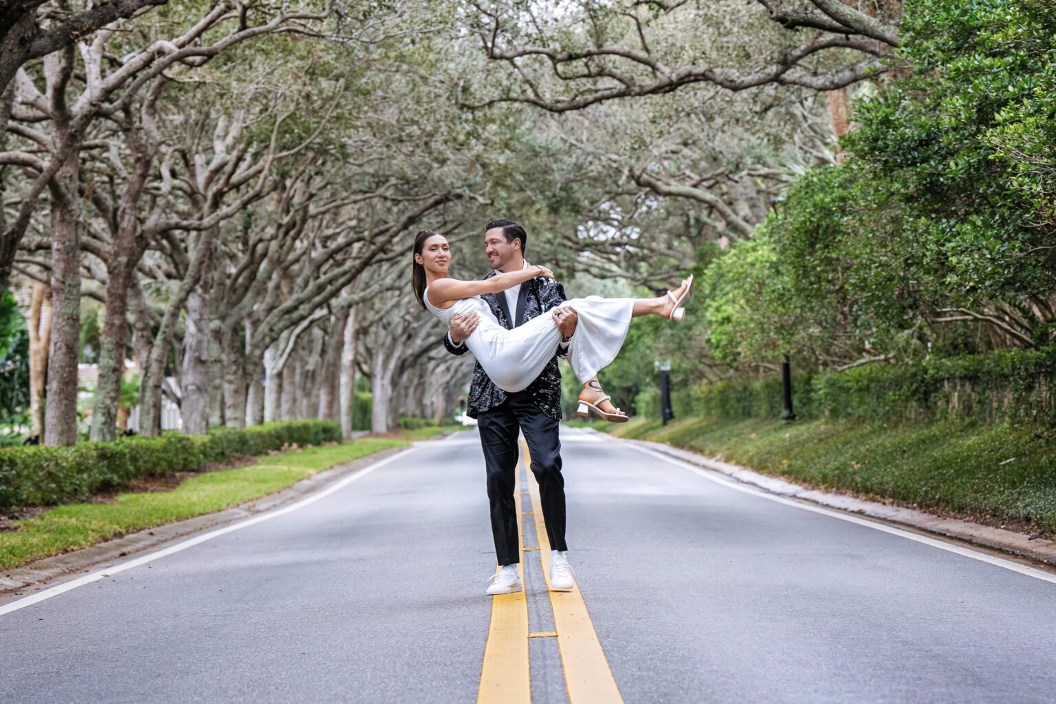 Bride and groom wedding portrait at Jonathan’s Landing in Jupiter, Florida — the groom lifting his bride under the canopy of oak trees in a quiet, romantic moment. Captured by South Florida wedding photographer David Scarola.