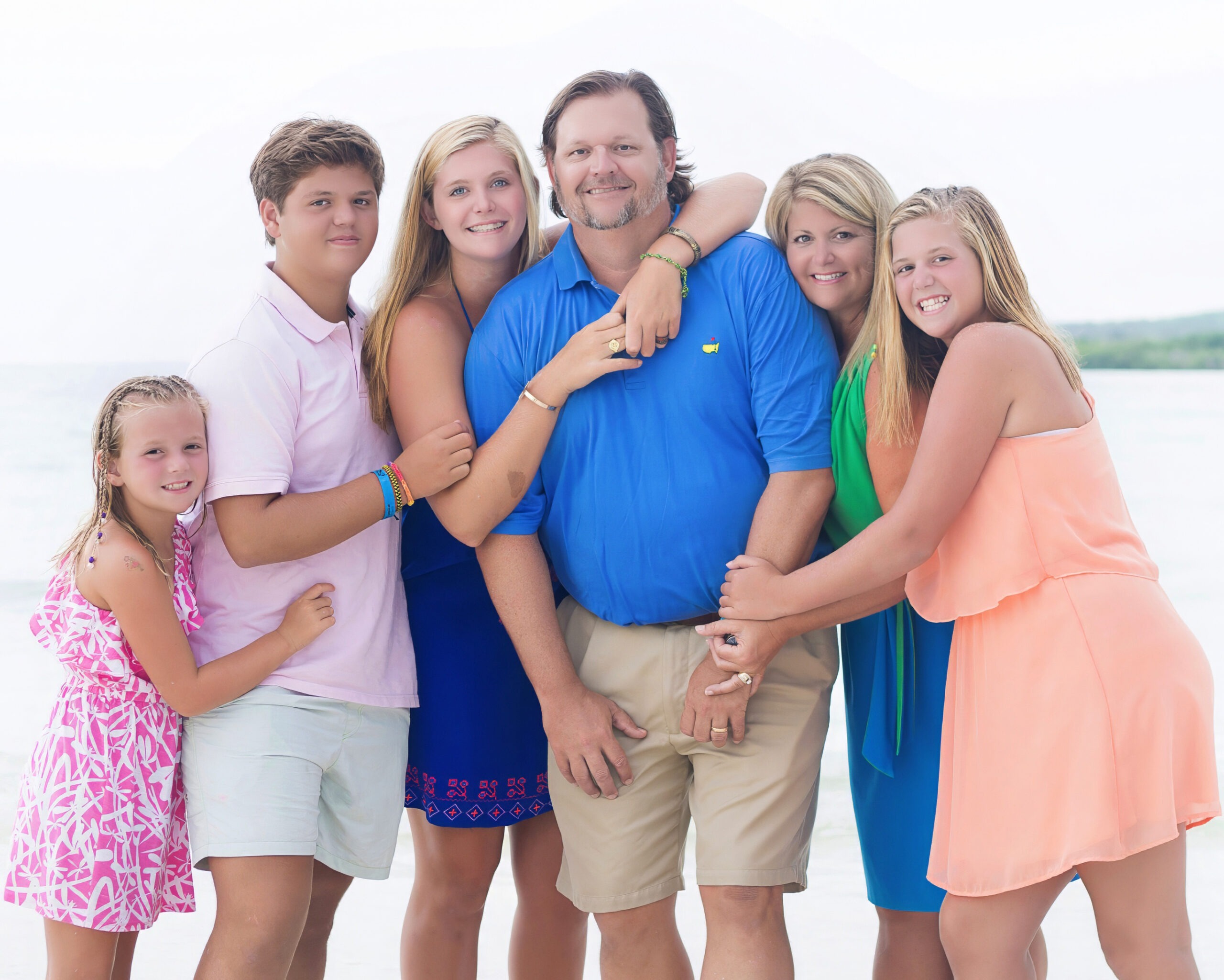 The Kirk family posing on a beach in Jamaica, at the Jamaica Sands beach resort, while world class traveling family photographer and master portrait artist, David Scarola guides mom, dad and the 4 kids throughout a series of poses.