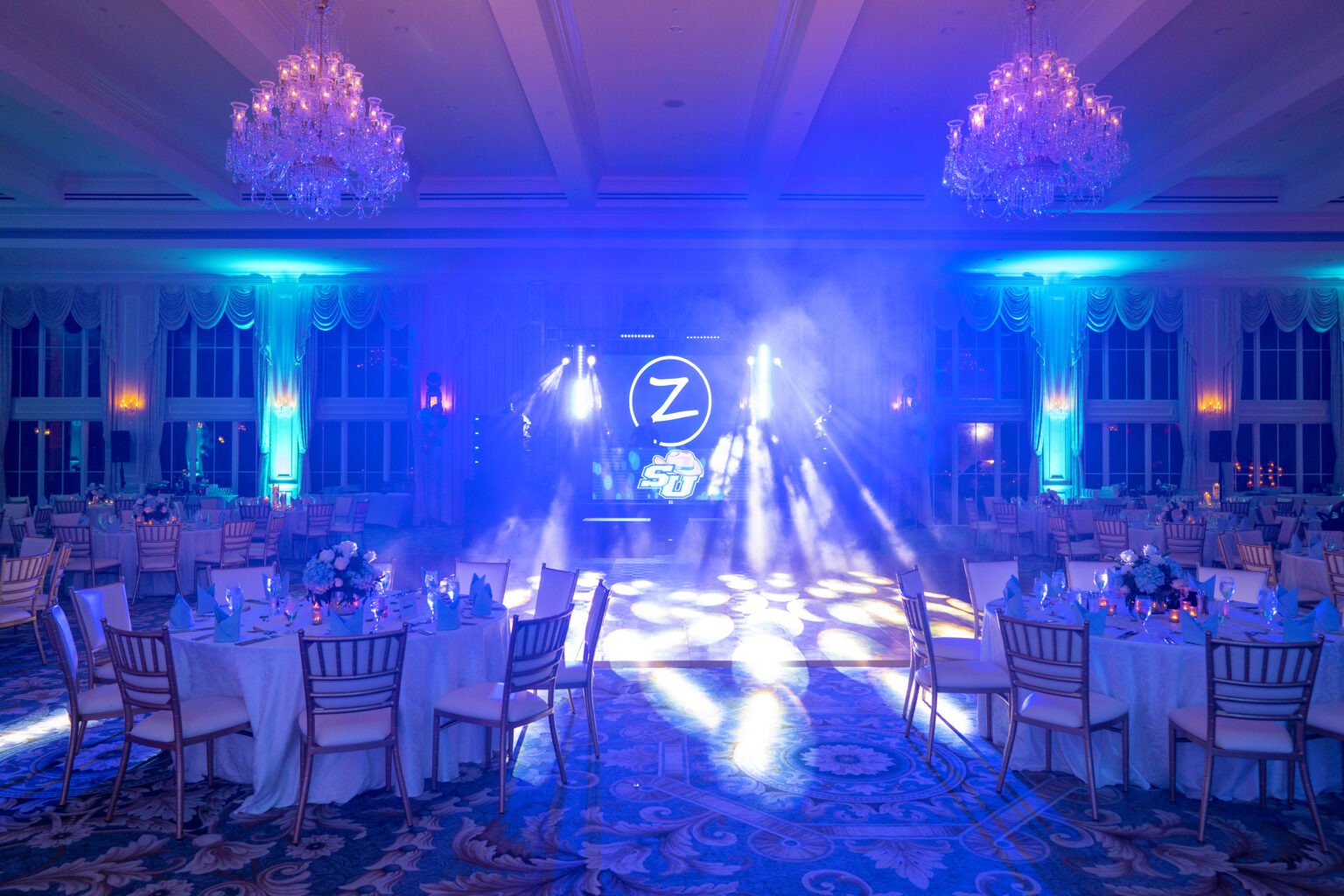Elegant ballroom illuminated in blue and violet light for a luxury graduation celebration at Trump National in Jupiter Island, photographed by David Scarola Photography.