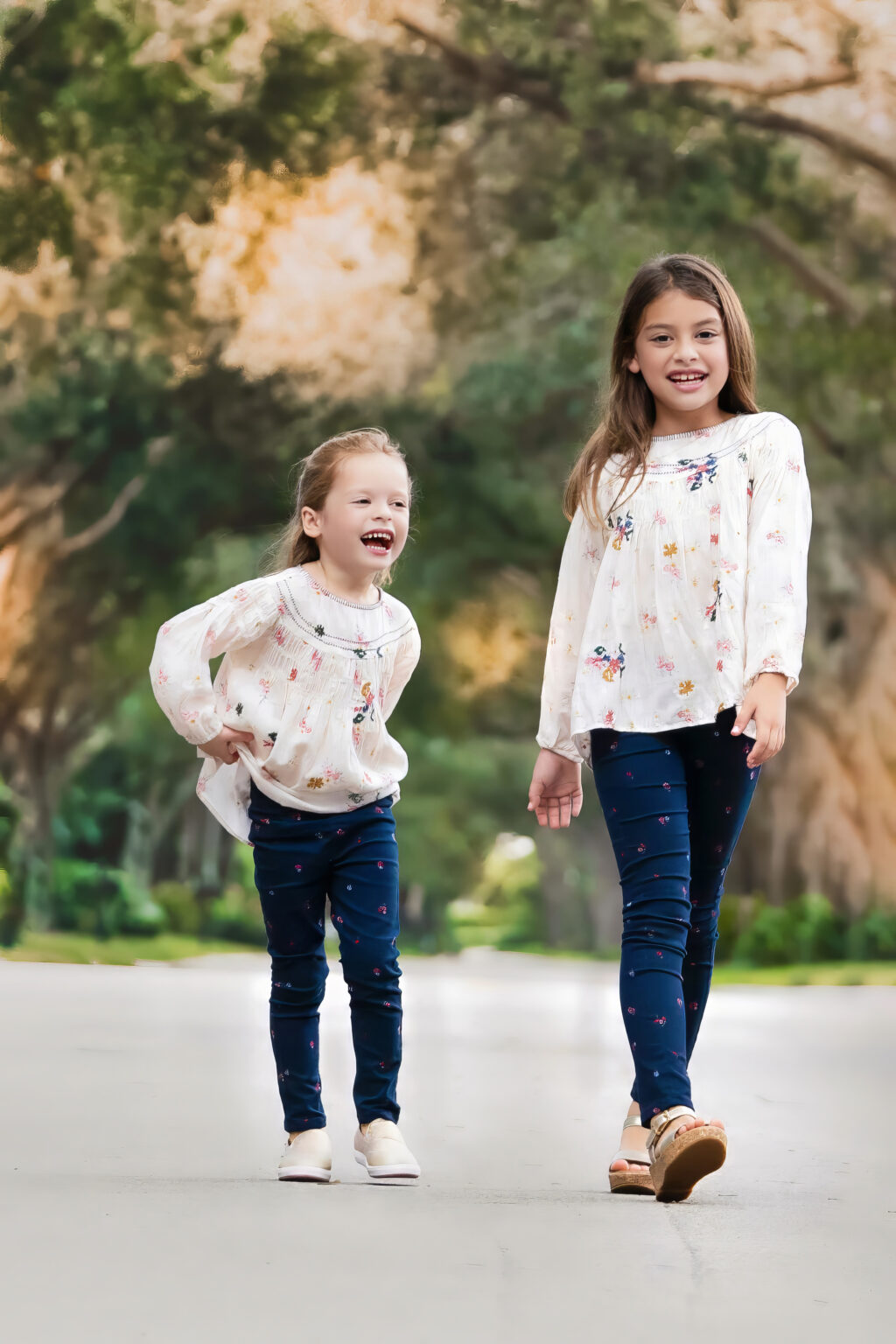 A sassy sister moment at sunset in Admirals Cove in Jupiter, Florida while top family photographer David Scarola is directing a family photo shoot on a gorgeous stretch of road, making for a stunning backdrop.
