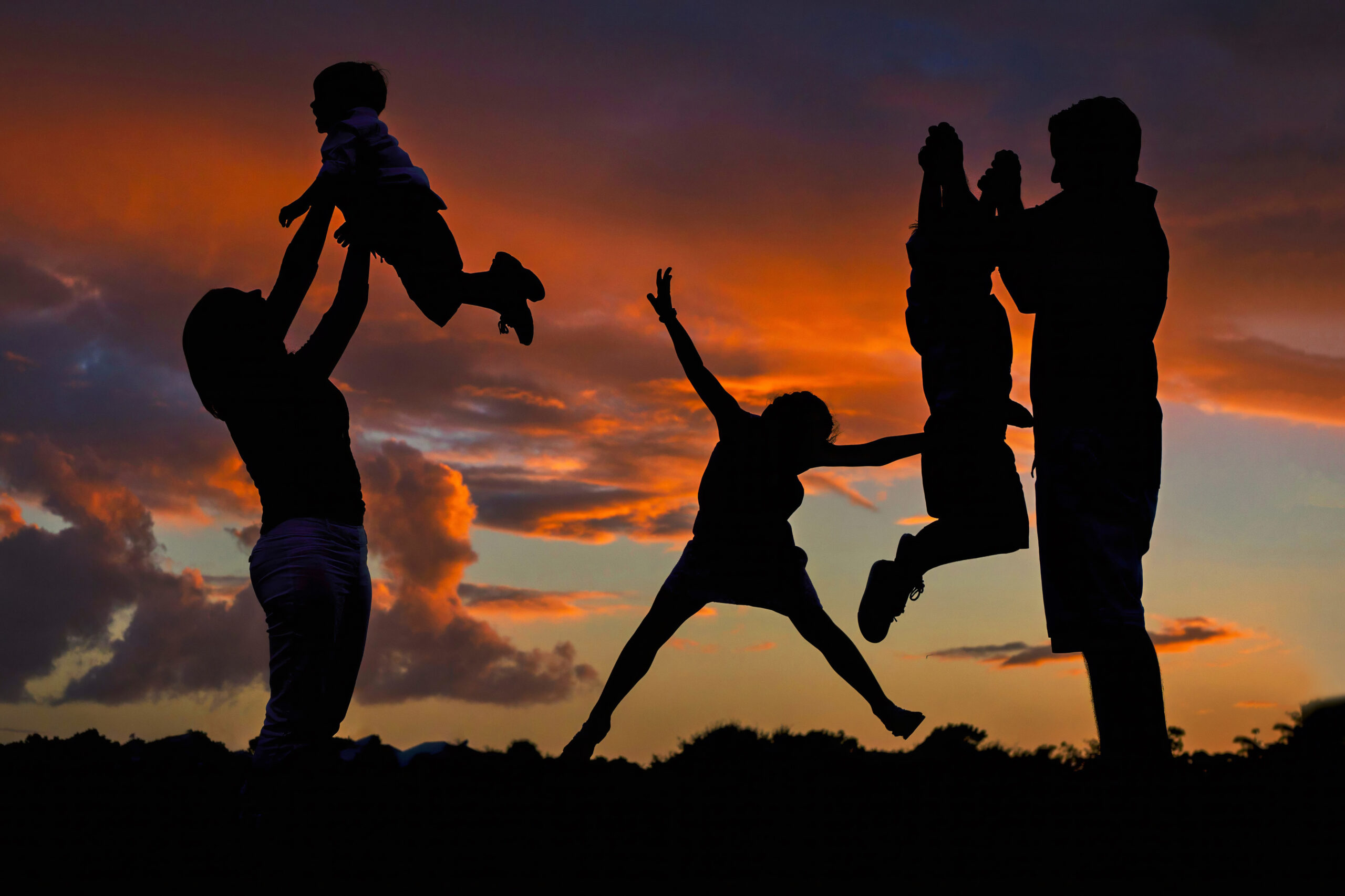 A gorgeous silhouette of a family of 5 playing at sunset on the golfcourse in Admirals Cove, in Jupiter, Florida, during their annual family photo shoot with the world renowned portrait artist, David Scarola.