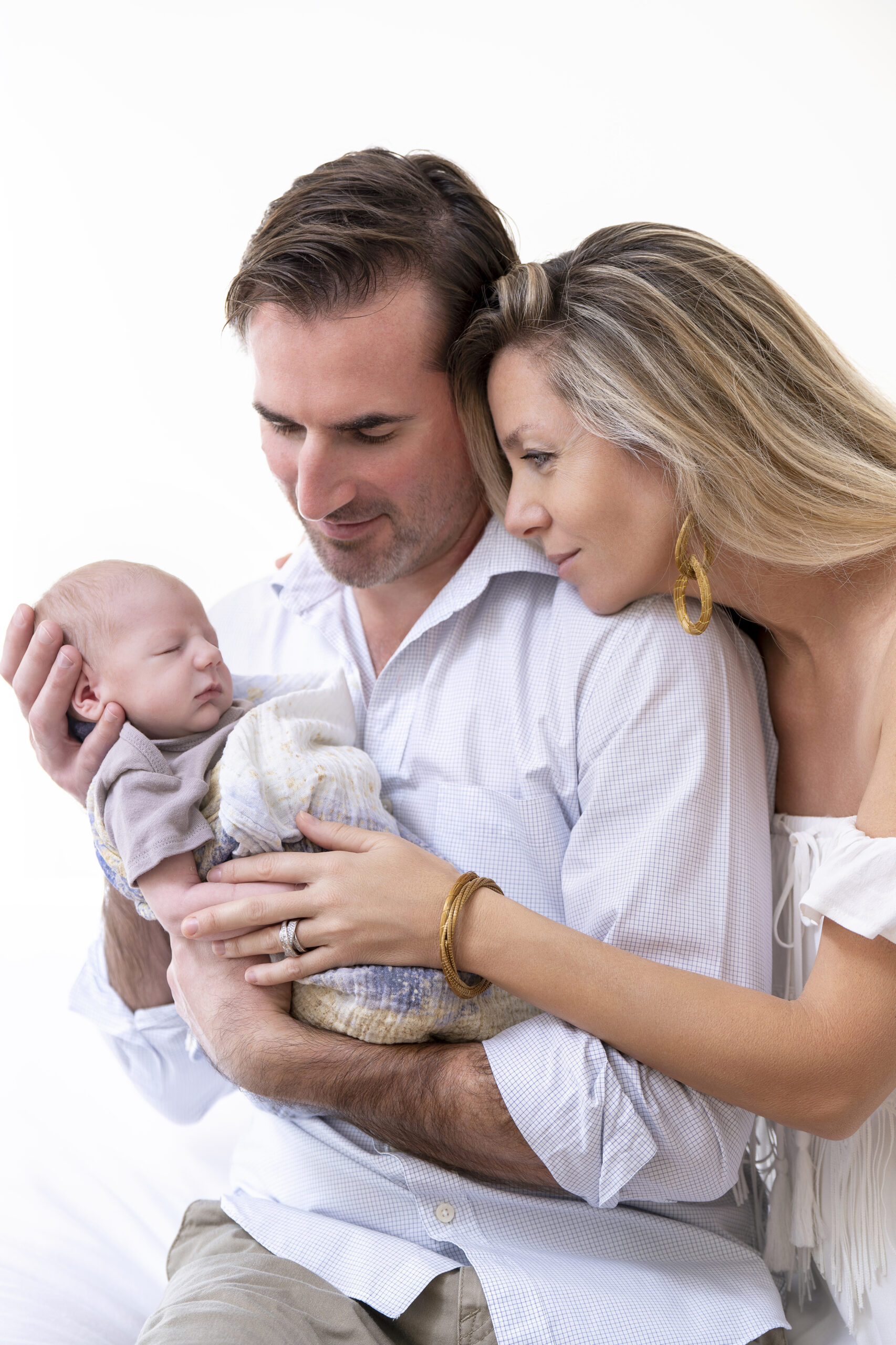 Newborn family portrait of mom and dad tenderly holding their baby Vance, photographed in soft natural light by David Scarola Photography, master of Palm Beach newborn photography, family portraits, and lifestyle art sessions.