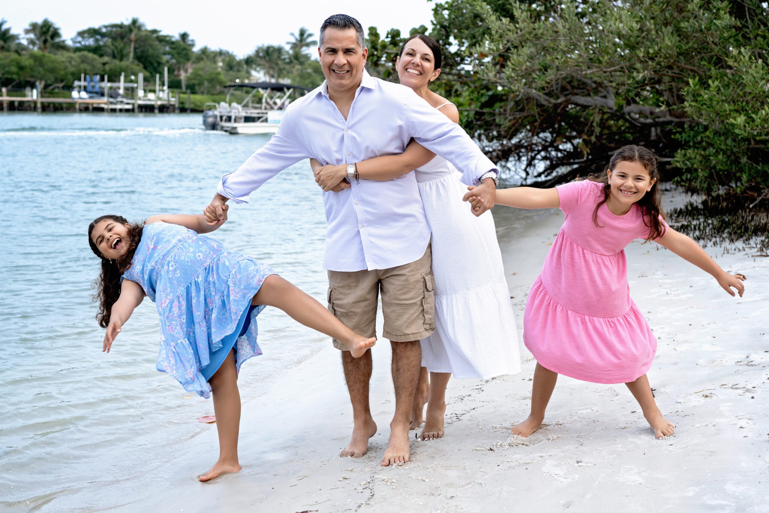 The Gomez Family enjoying a joyful family photo shoot on Jupiter Island beach — parents and two daughters laughing together by the water, captured by David Scarola Photography. A bright and playful family portrait session in Jupiter, Florida, celebrating love, connection, and life by the sea.
