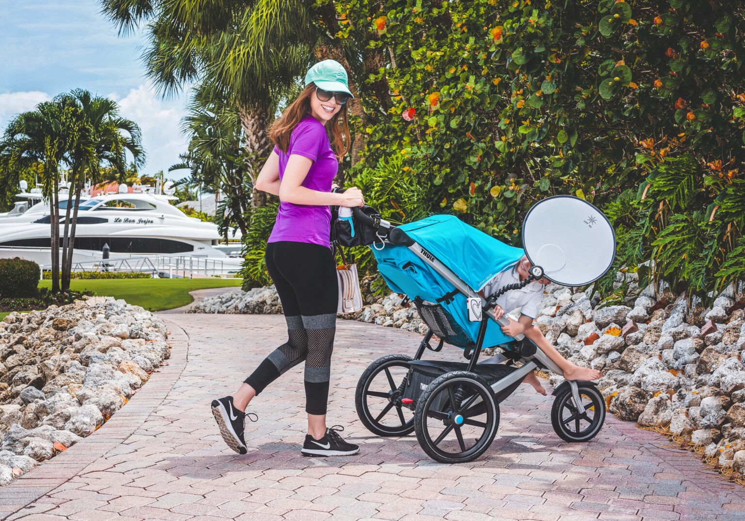 Lifestyle and product photograph of a mom on the go pushing a bright blue Nikiani stroller with built-in sunshade during a Nikiani Baby Products brand shoot at Admirals Cove in Jupiter, Florida, captured by David Scarola, one of the top commercial and lifestyle photographers in Palm Beach and Jupiter. The mother, dressed in sporty attire and smiling toward the camera, embodies the Nikiani brand’s mission — smart, stylish, and functional products for modern families.David Scarola Photography, Nikiani Baby Products, Nikiani Inc photoshoot, Admirals Cove Jupiter Florida, Jupiter Island brand photography, Palm Beach commercial photographer, lifestyle photographer Florida, baby product photography, mom on the go marketing, luxury stroller photography, product lifestyle campaign, family lifestyle photography, fine art commercial photographer, Jupiter brand photographer, outdoor lifestyle photoshoot, modern parenting brand imagery, Scarola style photography, Florida product photographer, Nikiani strollers and sunshades, professional branding photography Palm Beach County.