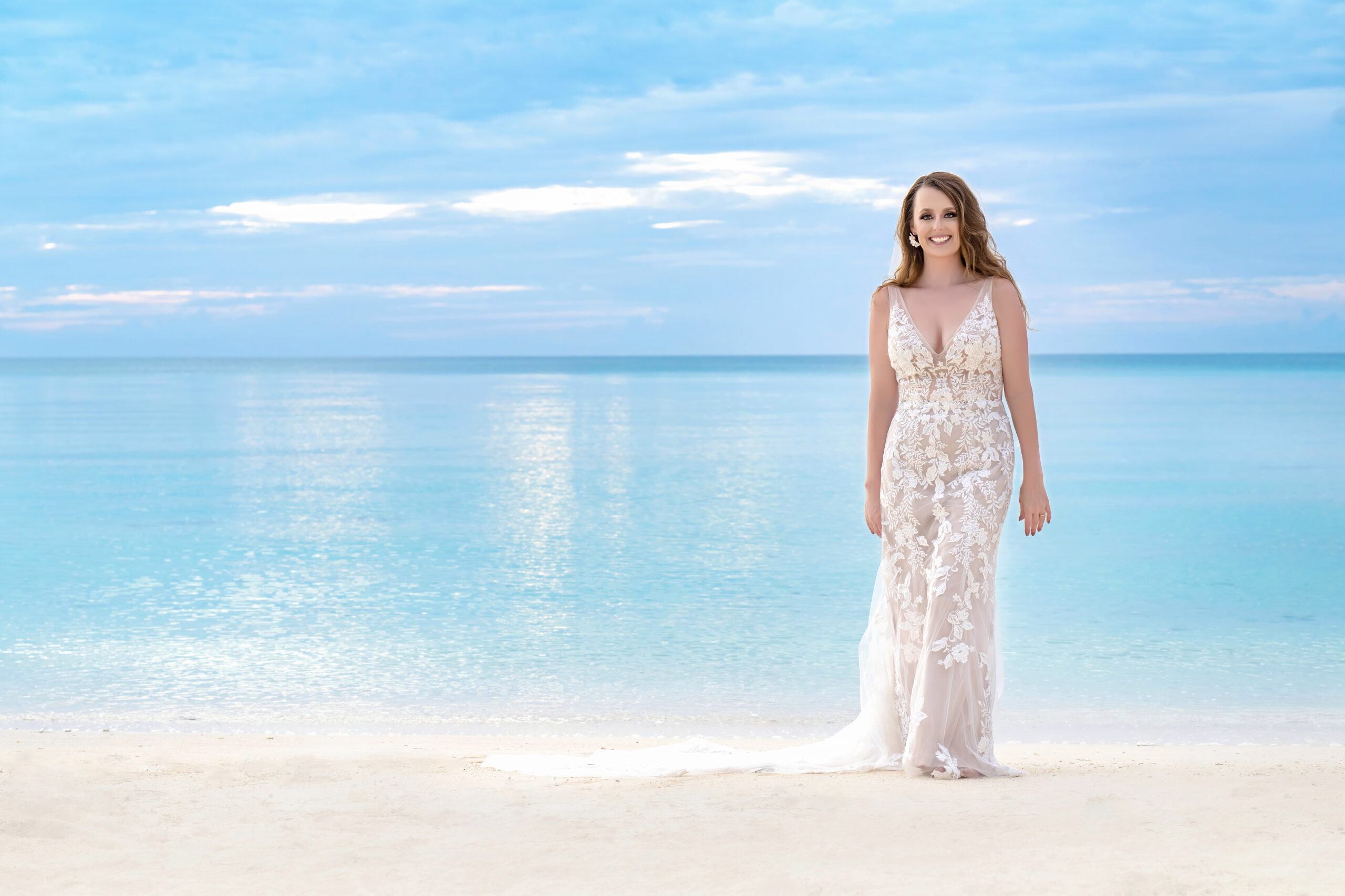 Bride standing barefoot on a pristine Eleuthera beach, her lace wedding gown shimmering against the turquoise waters of The Bahamas. Captured by award-winning destination photographer David Scarola, this fine-art portrait embodies elegance, serenity, and the radiant joy of island love at golden hour.