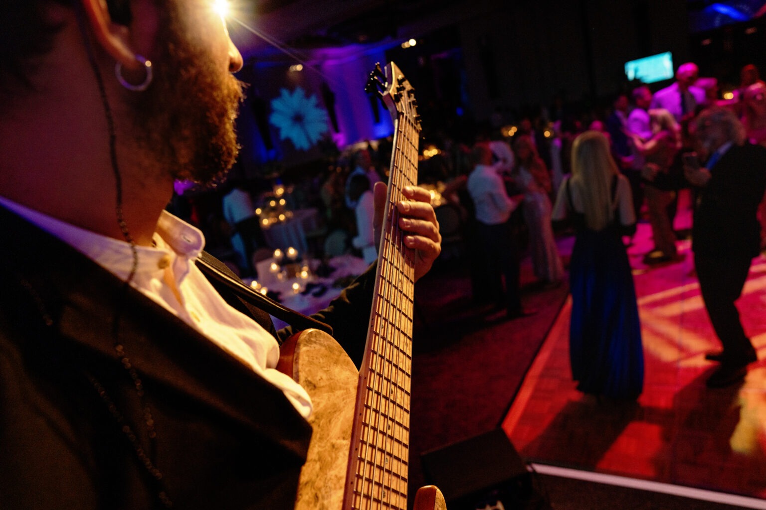 Live band performance at the Piper’s Angels Foundation Gala, Kravis Center, Palm Beach Island. Captured from the musician’s perspective, this artistic event photograph by David Scarola Photography highlights the vibrant energy, music, and elegance of the evening with guests dancing under candlelit ambience.