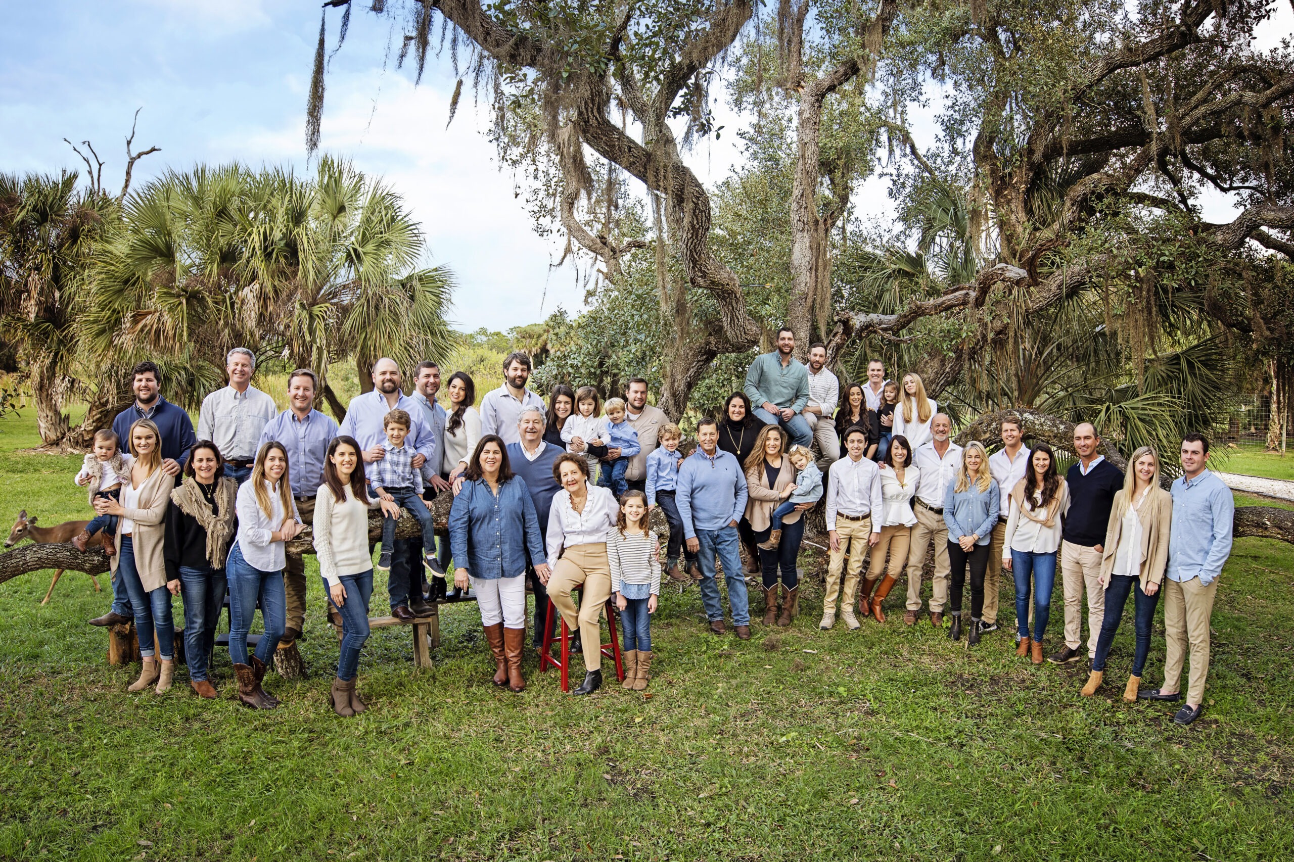 Multi-generation family portrait captured in Jupiter, Florida — three generations gathered beneath oak trees and palms. Large extended family photo filled with joy, connection, and legacy, photographed by Palm Beach portrait artist David Scarola.