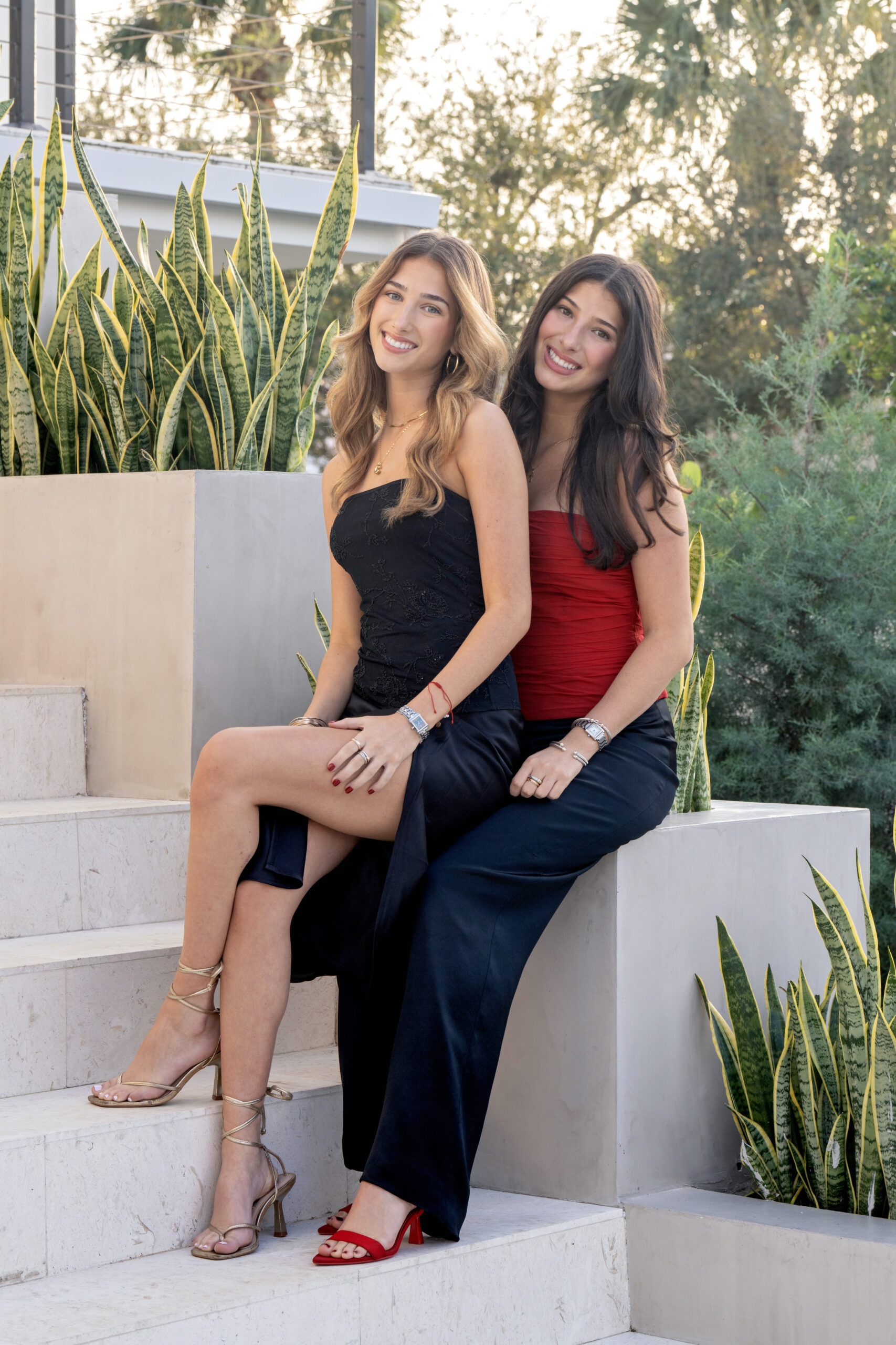 Sisters’ portrait in Palm Beach Island — two elegant young women in timeless black and red attire captured in soft golden light by master portrait artist David Scarola.