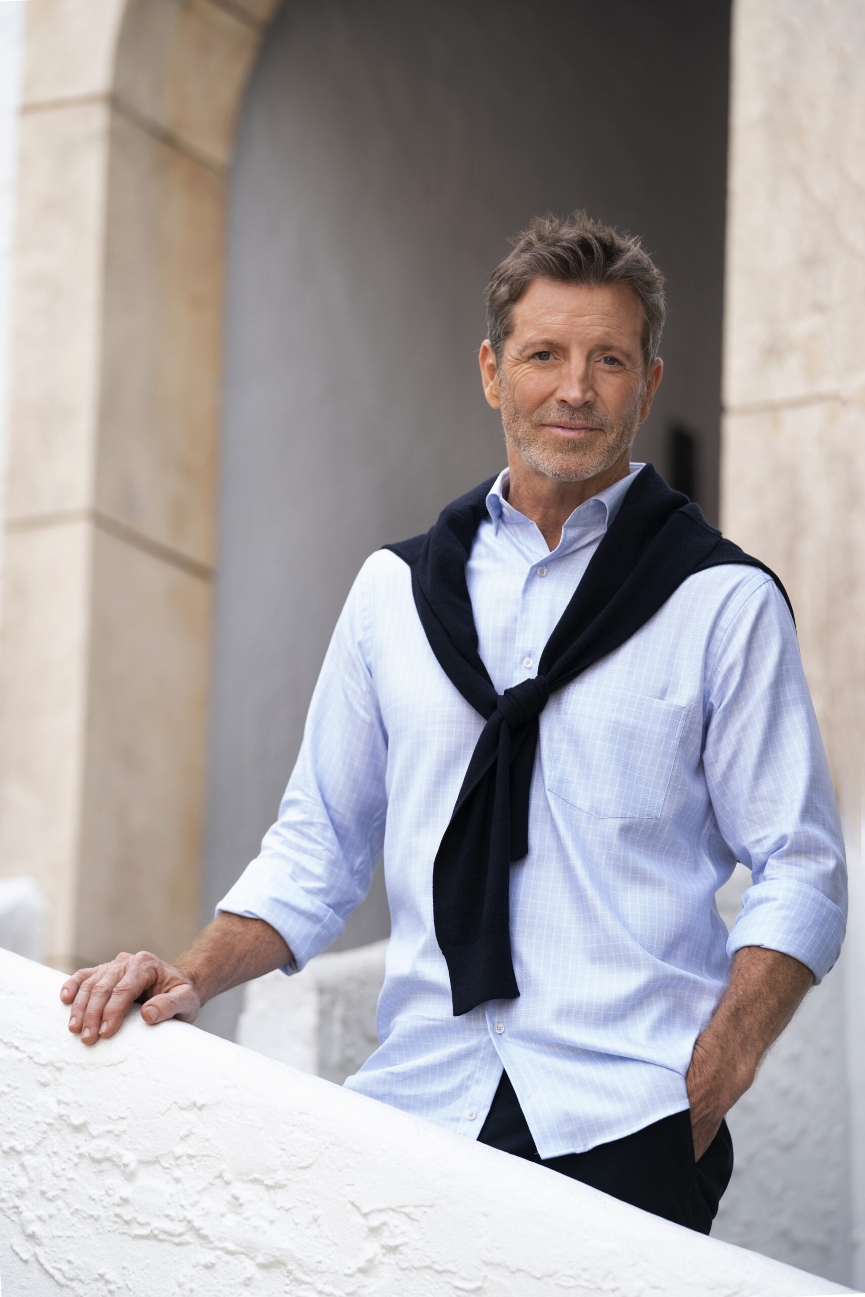 Branding and commercial portrait of a male model for Poeta Men, a luxury menswear store on Palm Beach Island, photographed by David Scarola, one of the top commercial and fashion photographers in Palm Beach and Jupiter, Florida. The model is dressed in an elegant light blue shirt with a navy sweater draped over his shoulders, standing against a soft architectural background that conveys sophistication, confidence, and timeless style — the essence of modern luxury menswear branding.David Scarola Photography, Poeta Men Palm Beach, Palm Beach Island fashion photographer, Jupiter Florida commercial photographer, luxury menswear photography, men’s fashion branding, professional lifestyle photographer Florida, fine art commercial photography, fashion campaign Palm Beach, retail brand photography, Poeta Men photoshoot, male model portrait Palm Beach, high-end branding photographer, professional photographer Jupiter, fashion and lifestyle photography Palm Beach County, Scarola style photography, modern menswear photography, elegant male fashion portrait, best commercial photographer Florida, luxury boutique photography.