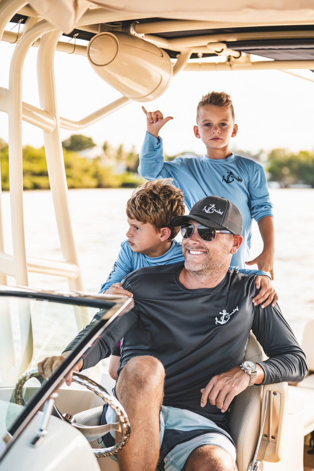 Lifestyle and branding photograph featuring a father and his two sons on a sunset boating outing in Jupiter, Florida, modeling JTown Apparel performance shirts and hats. Captured by David Scarola, one of the top lifestyle and commercial photographers in Palm Beach and Jupiter. The image highlights the brand’s coastal identity — comfort, adventure, and family — embodying the JTown Apparel mission to blend active wear functionality with laid-back Florida style.