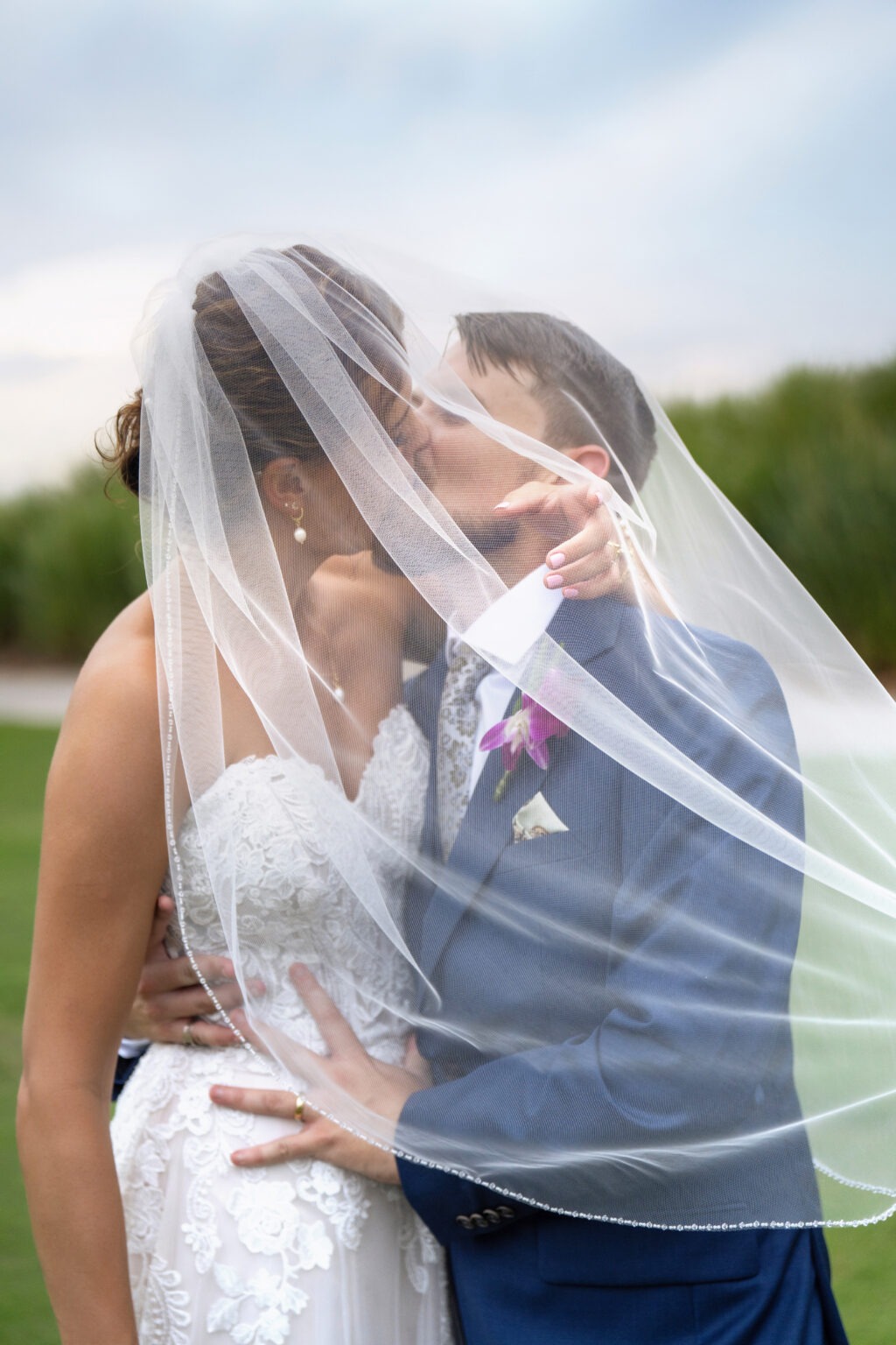 Bride and groom sharing a romantic kiss beneath her flowing veil at Jupiter Country Club on Jupiter Island, Florida — a moment of intimacy and elegance captured in soft natural light by David Scarola, Florida’s premier wedding photographer and master of fine-art portraiture celebrated for creating emotional, timeless, and luxurious wedding imagery.