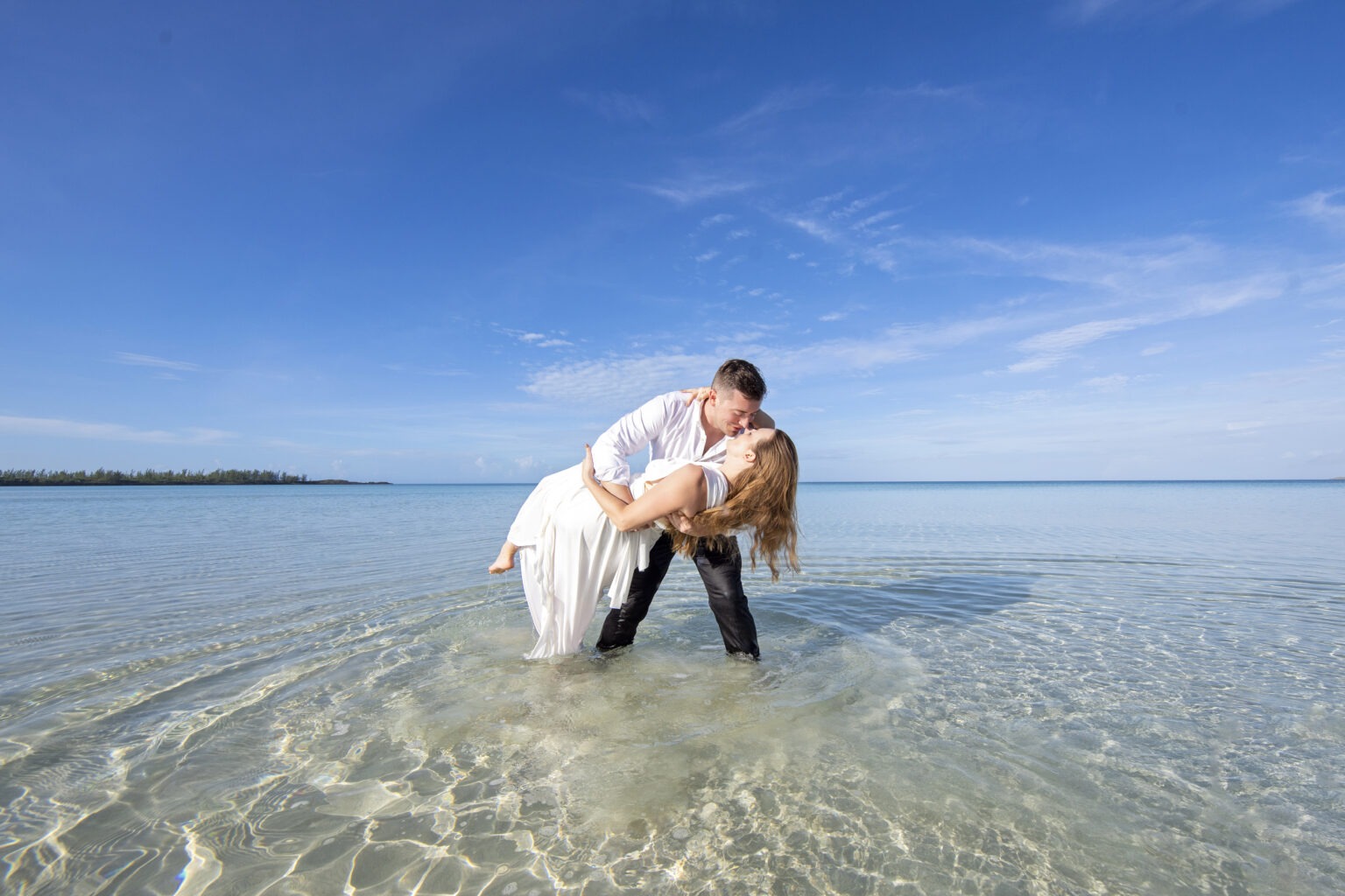 Bride and groom share a romantic dip and kiss in the crystal-clear turquoise waters of Eleuthera, Bahamas. Captured by world-class destination wedding photographer David Scarola, this fine-art image blends adventure, intimacy, and tropical beauty under a vast blue sky — a signature of Scarola’s vibrant, storytelling style.