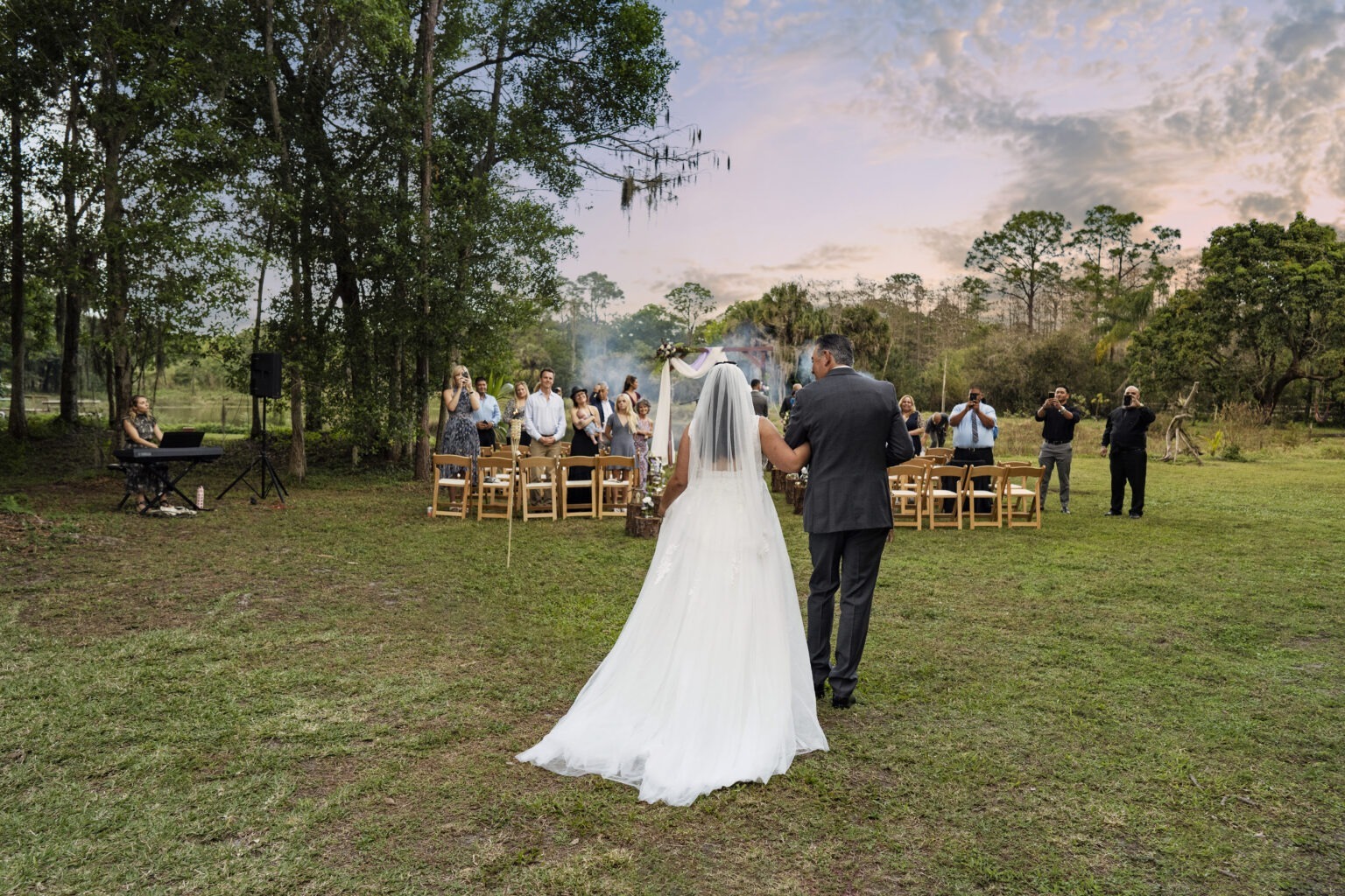 Bride walking arm-in-arm with her father down the aisle at an intimate outdoor wedding on private land in Jupiter Island’s Hawks Landing. Captured in natural light by David Scarola Photography, showcasing emotional, artistic, and professional wedding coverage that connects deeply with the moment.