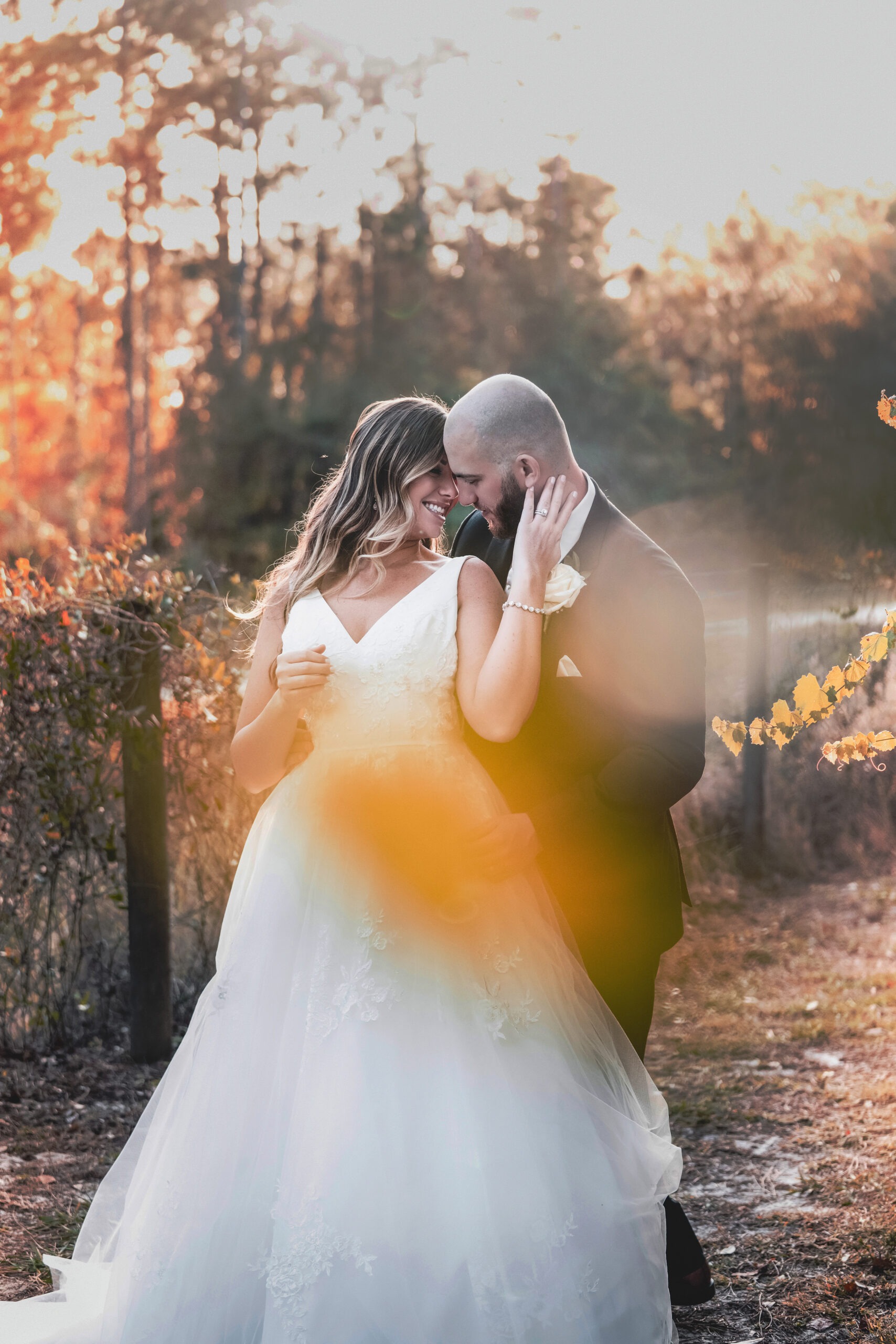 Bride and groom embrace in golden sunset light during a Hawks Landing wedding in Jupiter, Florida, captured by Palm Beach wedding photographer David Scarola — a glowing, romantic moment surrounded by soft autumn hues and warmth.