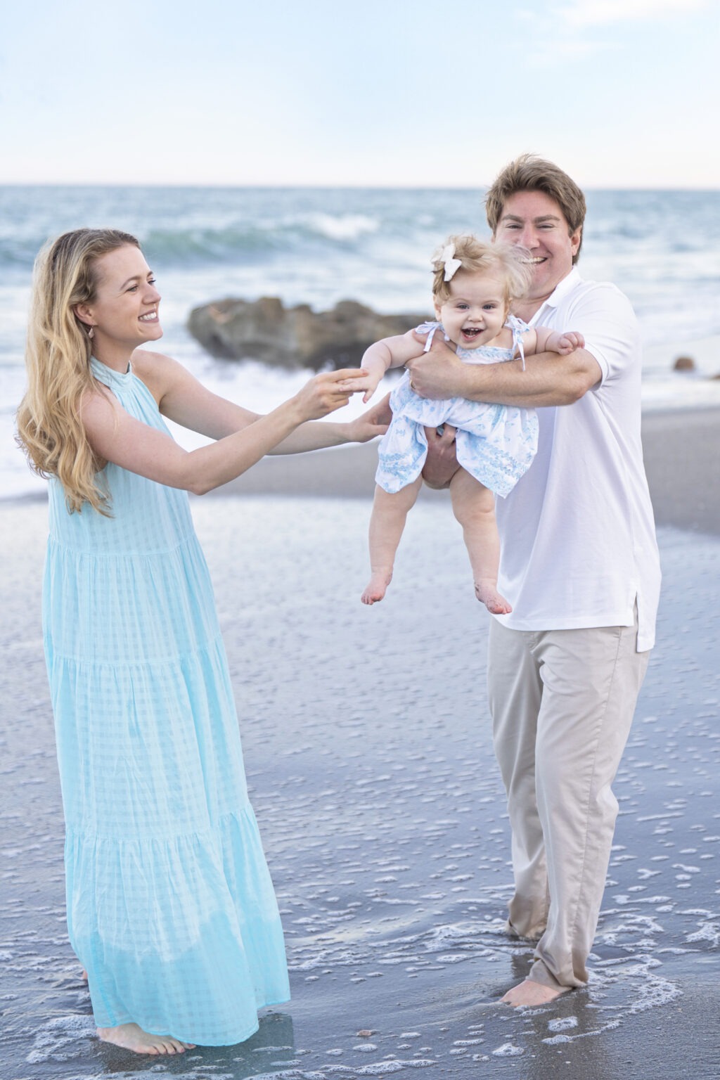 A joyful family of three during their baby’s first beach portrait session in Palm Beach, captured by master portrait photographer David Scarola.family photographer Palm Beach, baby beach portraits, first-year portraits Jupiter Island, family of three photo session, Palm Beach lifestyle photographer, professional baby photographer Florida, luxury family portraits, candid family photography, master portrait artist Florida, David Scarola Photography, family beach photography, best family photographer USA, fine art family portraits Palm Beach, baby milestone photography.